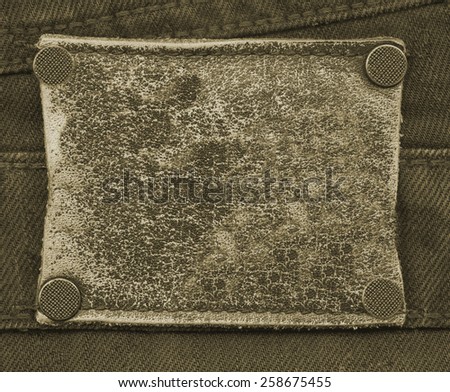 brown old and worn  blank leather jeans label on brown textile background