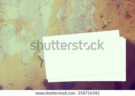 Close up of a stack of blank business cards on a old wall with peeled of paint surface