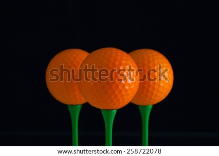 Golf balls and green wooden tees on a black background