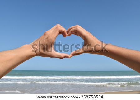 Hand in heart form love blue sky on beach.