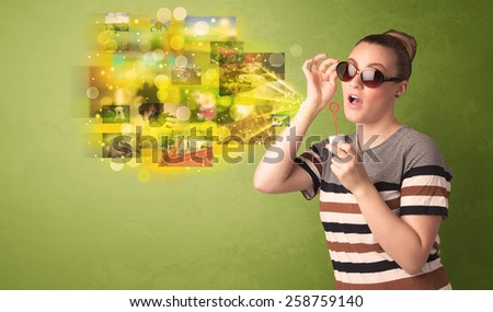 Cute girl blowing colourful glowing memory picture concept on green background