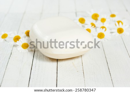 soap bar with chamomile flowers on white wood surface