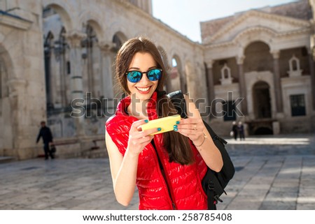 Young woman dressed in sportswear with smart phone traveling in the old city center