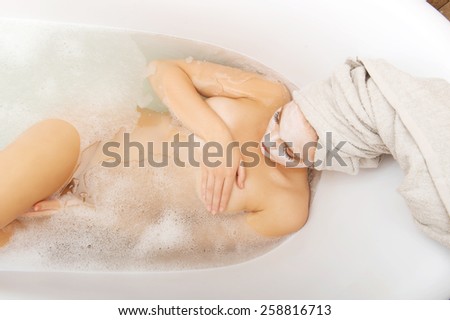 Young spa woman relaxing in bathtub with cream moisturizer. 