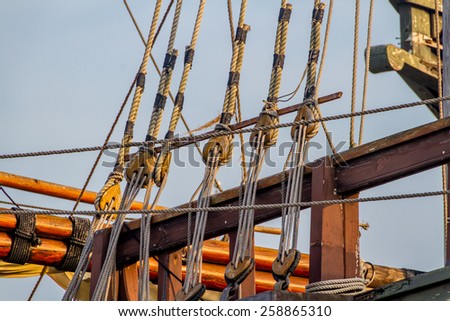 Planks, ropes, pulleys, tackle, and rigging of an old replica of a 1400's era sailing ship.