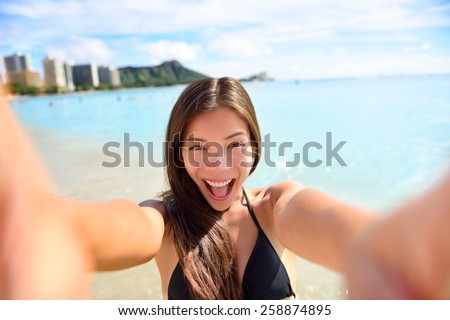 Selfie fun woman taking picture at beach vacation. Summer holiday girl happy at smartphone camera taking self-portrait on her Hawaiian travel vacations in Waikiki, Honolulu city, Oahu, Hawaii, USA.