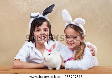 Kids with bunny ears holding their favorite pet - a white rabbit
