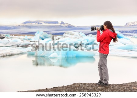 Nature landscape photographer taking picture photos with SLR camera on Iceland Jokulsarlon glacial lagoon / glacier lake. Woman taking photograph of beautiful Icelandic nature with Vatnajokull.