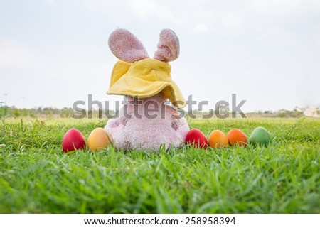 Colorful easter eggs and rabbit wear hat on green grass