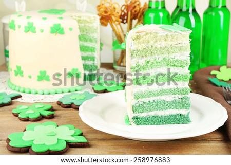 Still life with sliced cake and green beer for Saint Patrick's Day on wooden table and blurred background