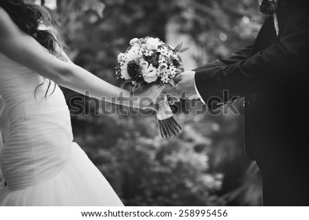 Hands of newlywed couple in love, wedding on summer day.  Picture in black and white. 
