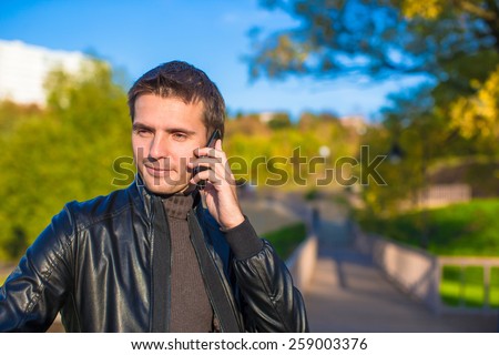 Young man with talking by phone outoors
