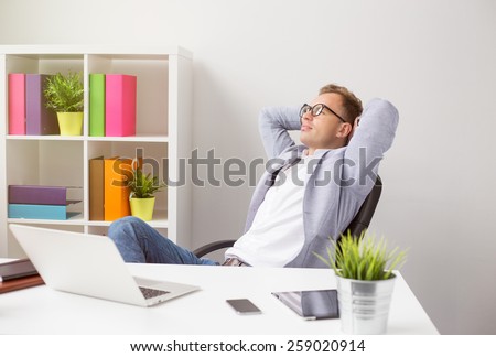 Relaxed businessman sitting in chair with hands behind head Royalty-Free Stock Photo #259020914