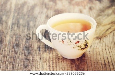 Camomile tea in a vintage white cup with daisy flowers on wooden table
