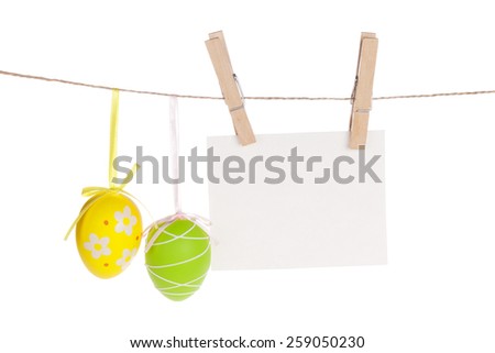 Colorful easter eggs and blank photo frame hanging on rope. Isolated on white background