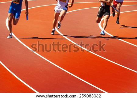 Running athletes at stadium in relay race athletics competition   Royalty-Free Stock Photo #259083062