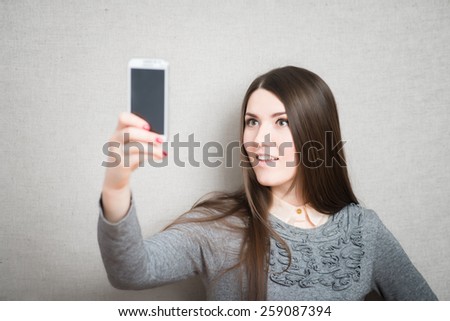 Happy flirting young girl taking pictures of herself through cell phone
