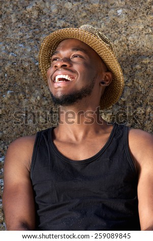 Close up portrait of a happy young man laughing with hat