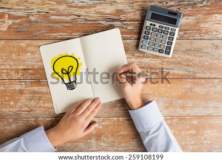 business idea, education, people and technology concept - close up of female hands with calculator, pen and lighting bulb drawing in notebook on table