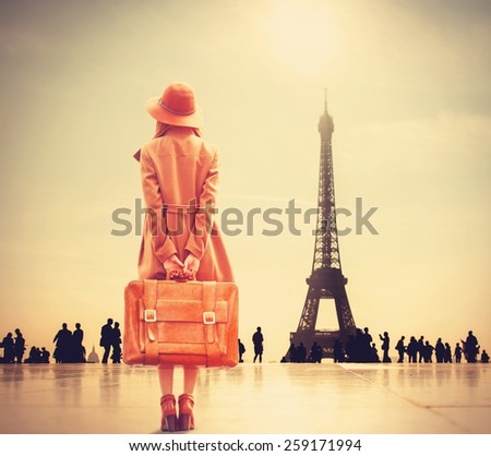 Redhead girl with suitcase on Eiffel tower background
