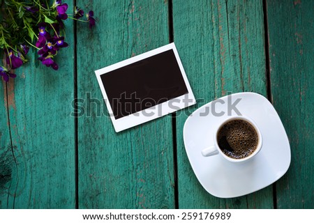 Empty photo card and a cup of coffee on old green wooden board, memory concept