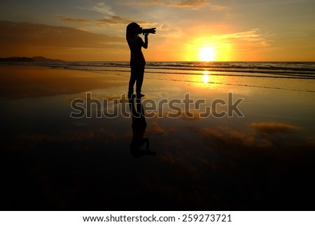 silhouette woman take picture on sunset background
 (Shallow DOF, slight motion blur)