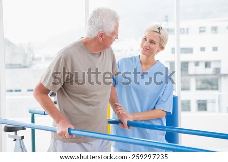 Senior man walking with therapist help in fitness studio Royalty-Free Stock Photo #259297235
