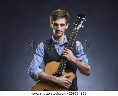 Young handsome guitar player. Studio shot on black background.