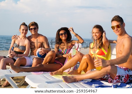 Group of multi ethnic friends with drinks relaxing on a beach