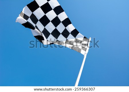 Checkered flag flying on blue sky background