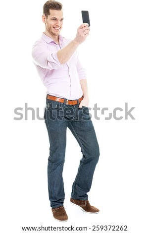 Selfie Photo - Full length portrait of a young man taking a selfie with his smart phone, isolated on white background