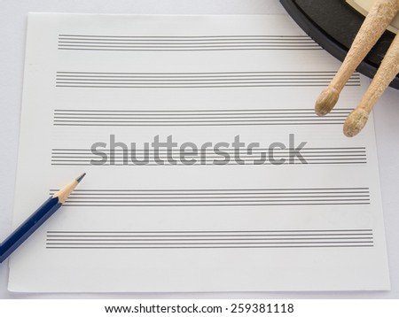 Music note sheet with pencil and drum sticks on white background, Selective focus on Sharpness of pencil
