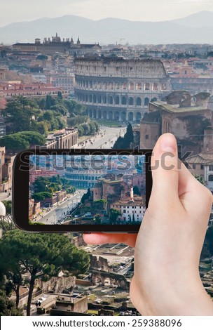 travel concept - tourist taking photo of street Via dei Fori Imperiali to Coliseum, Rome, Italy on mobile gadget
