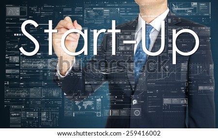 the businessman is writing Start-Up on the transparent board with some diagrams and infocharts with the dark elegant background