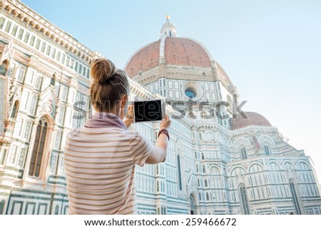 Young woman taking photo with tablet pc of cattedrale di santa maria del fiore in florence, italy. rear view