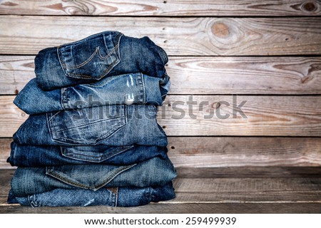 jeans stacked on a wooden background Royalty-Free Stock Photo #259499939