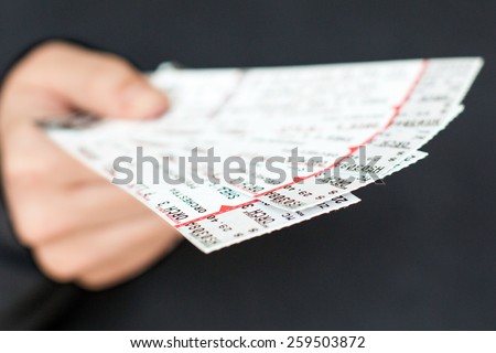Tickets being held in a hand. Royalty-Free Stock Photo #259503872