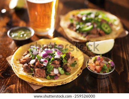 authentic mexican tacos with beer on wooden table shot with selective focus