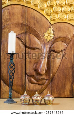 buddha face carving, thai colorful handcraft bowls, white candle on vintage green candlestick for interior concept