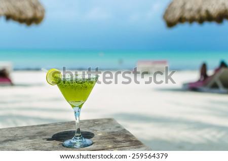 Fresh cold tasty Margarita cocktail with lime and ice on a table at tropical white sand beach