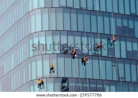 Washers wash the windows of modern skyscrape Royalty-Free Stock Photo #259577786