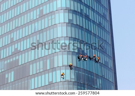 Washers wash the windows of modern skyscrape Royalty-Free Stock Photo #259577804