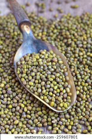 Dry green Mung beans in the scoop on wooden table, selective focus - some beans in focus, some are not