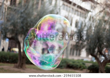 Single iridescent soap bubble floating through air