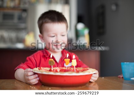 Little boy looking at his birthday cake with burning candles