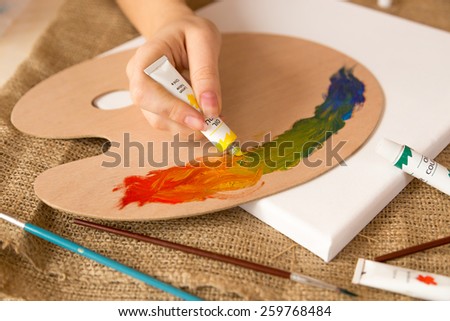 Closeup photo of artist squeezing oil paint on pallet from tube 