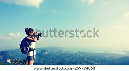 woman hiker photographer taking photo at mountain peak  