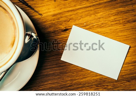 White card and coffee cup on wooden background - vintage effect style pictures