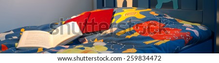 Two open books left on colorful children bed