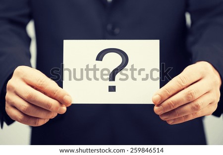 picture of man in suit holding card with question mark